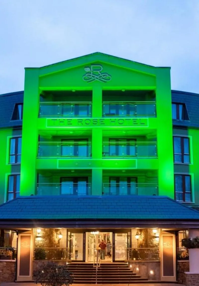 Exterior view of the lee rose hotel at twilight with vibrant green lighting accentuating its modern design and signage.