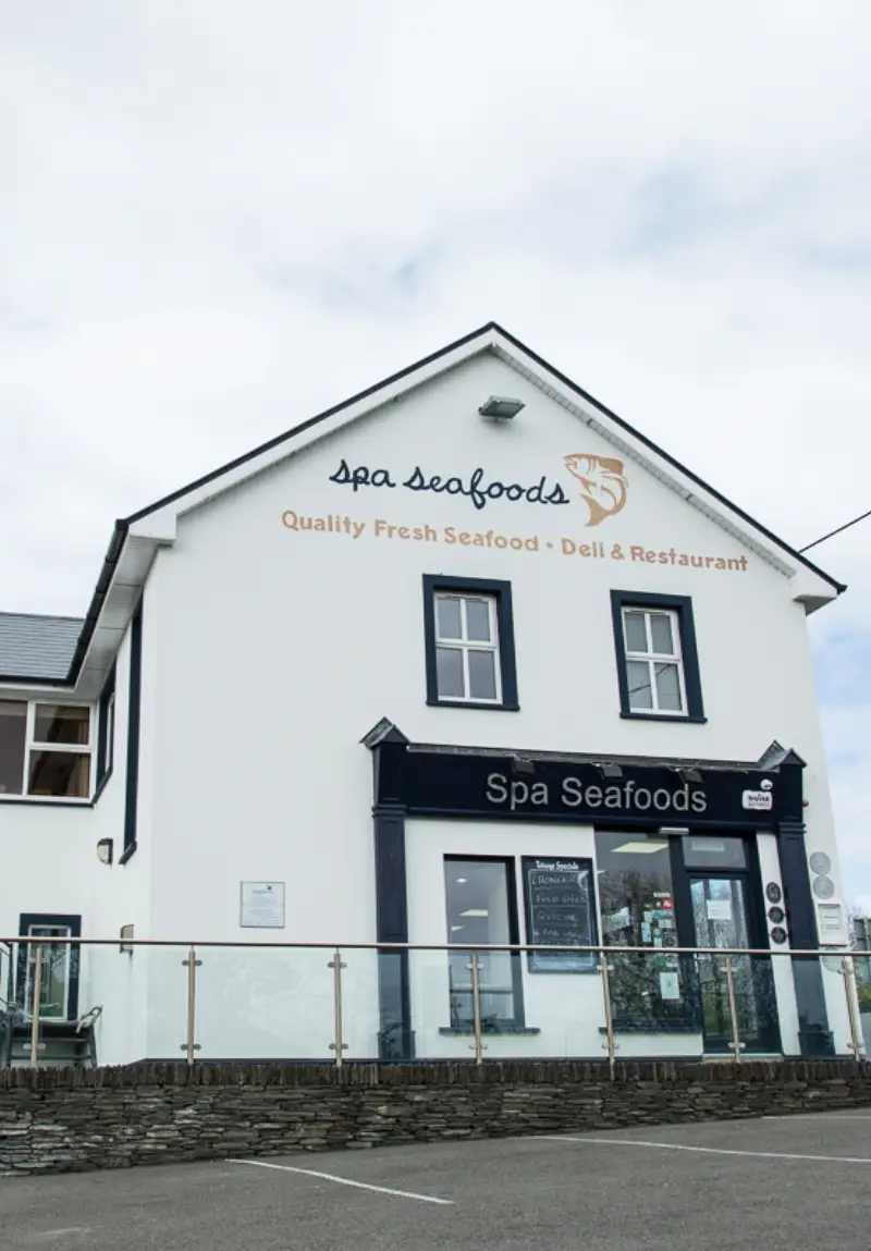 Exterior view of Spa Seafoods, a two-story white building with signage, serving quality fresh seafood and functioning as a deli and restaurant.